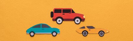 top view of paper cut cars and black rent lettering on orange background, panoramic shot