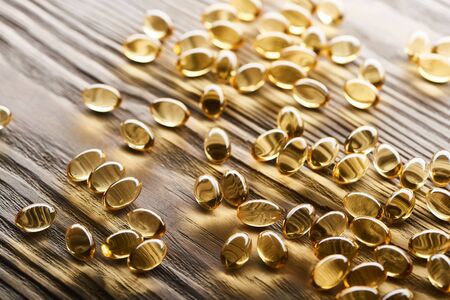 golden fish oil capsules scattered on wooden tableの写真素材