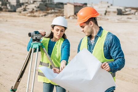 Surveyor with digital level pointing on blueprint to colleagueの写真素材