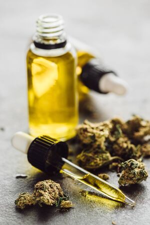 selective focus of dropper with hemp oil, medical marijuana buds and bottles on stone surfaceの写真素材