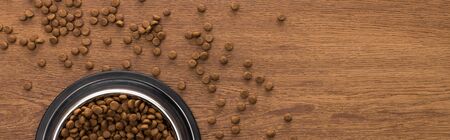 top view of dry pet food in silver bowl on wooden table, panoramic shot