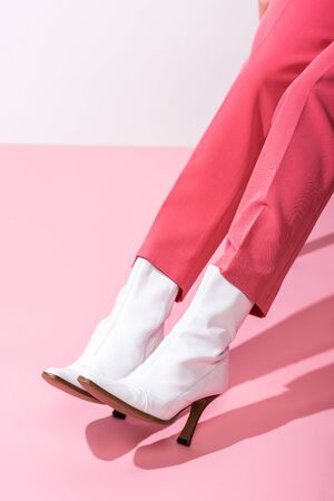 cropped view of girl in boots on white and pinkの写真素材