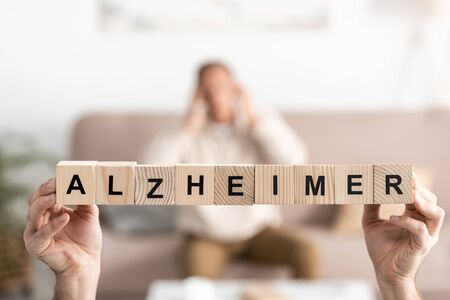 cropped view of senior woman holding wooden cubes with alzheimer lettersの写真素材