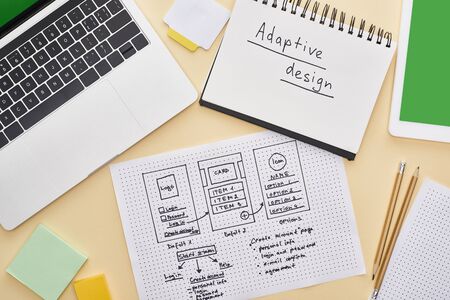 top view of gadgets near website design template and notebook with adaptive design lettering on...