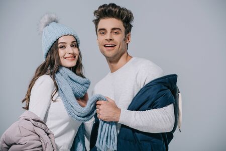 cheerful young couple posing in winter outfit, isolated on greyの写真素材