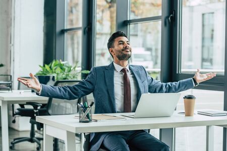 happy businessman showing wow gesture while sitting at workplaceの写真素材