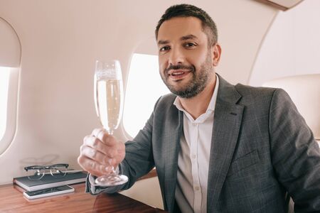 handsome businessman holding champagne glass in private jet