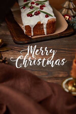 traditional Christmas cake with cranberry on wooden table with brown napkin and white merry Christmas letteringの写真素材