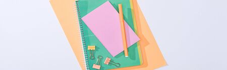 panoramic shot of notebooks, binder clips, felt tip pen and paper isolated on white