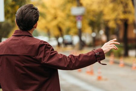 Back view of man catching taxi on street