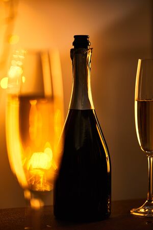 glasses and bottle of sparkling wine with yellow christmas lights bokehの写真素材
