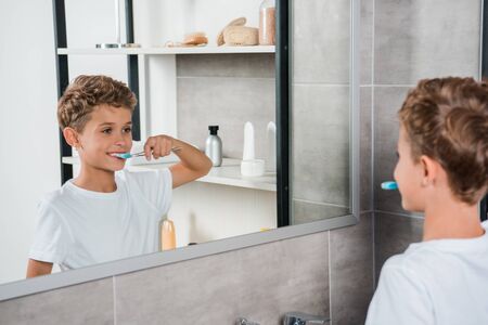 selective focus of happy kid brushing teeth in bathroomの写真素材