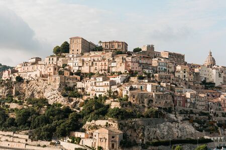 sunshine on trees near small houses in ragusa, italyの写真素材