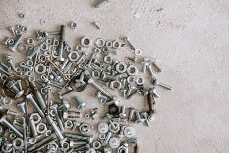 top view of metal screws and nails scattered on grey background