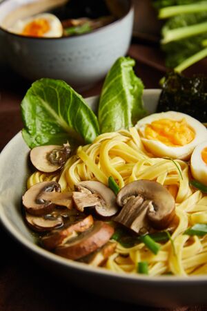close up view of traditional spicy ramen in bowl on brown napkin on stone surfaceの写真素材