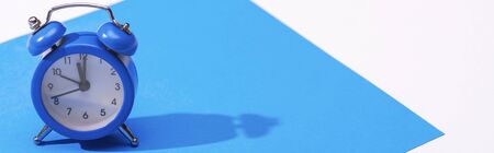panoramic shot of alarm clock and blue paper isolated on whiteの写真素材