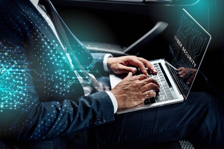 partial view of african american businessman using laptop with cyber security illustration in car