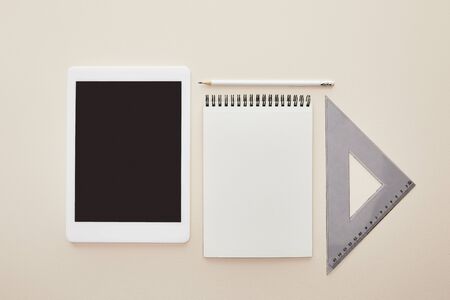 top view of digital tablet with blank screen near notebook isolated on beige