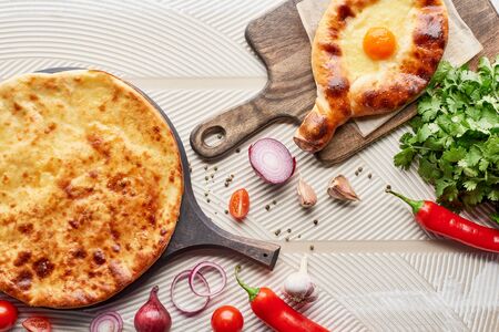 Top view of adjarian and imereti khachapuri with vegetables and spices on textured backgroundの写真素材