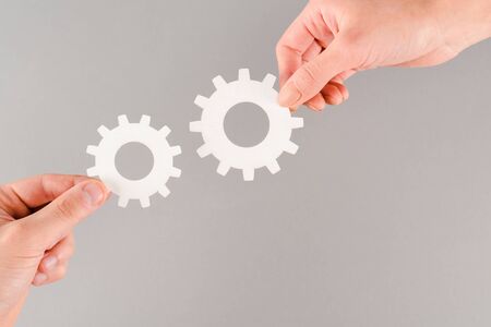 cropped view of people holding white gears isolated on grey