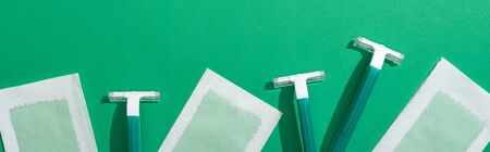 top view of green disposable razors and depilation wax stripes on green background, panoramic shotの写真素材