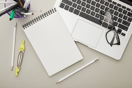 top view of notebook near stationery and laptop isolated on grey