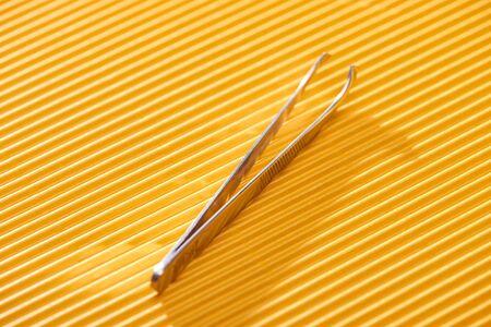 stainless steel tweezers on yellow textured backgroundの写真素材