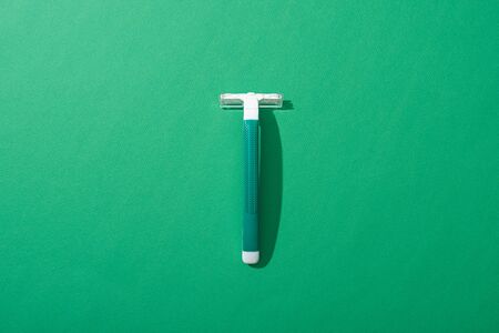 top view of green disposable razor on green backgroundの写真素材