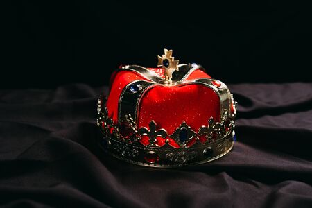 ancient red golden crown with gemstones on black cloth