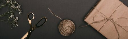 panoramic shot of craft christmas gift with scissors, flowers and twine on blackの写真素材