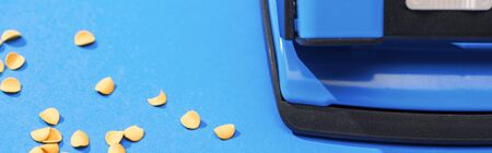 panoramic shot of holepunch with paper circles on blue backgroundの写真素材