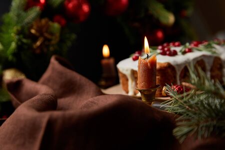 selective focus of traditional Christmas cake with cranberry near burning candles on wooden tableの写真素材