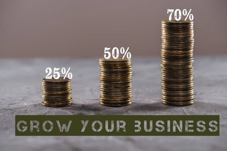 stacks of coins near percentage and grow your business inscription on stone surface isolated on grey, business conceptの写真素材