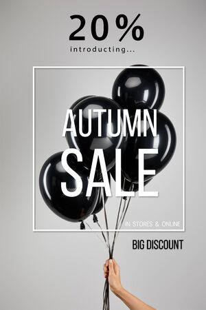 partial view of woman holding bunch of black balloons isolated on grey with 20 percent autumn sale illustration, black Friday conceptの写真素材