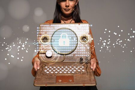 cropped view of steampunk woman in top hat with goggles showing vintage laptop with internet...