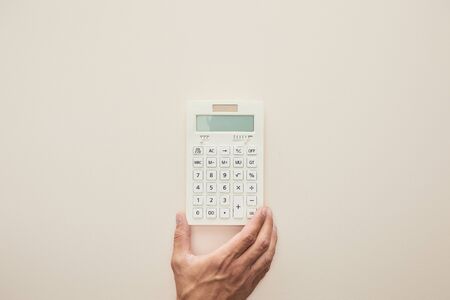 cropped view of man holding calculator isolated on beigeの写真素材