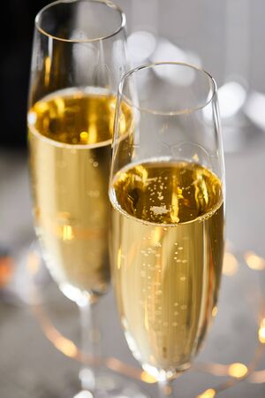 close up of glasses of sparkling wine with blurred yellow christmas lightsの写真素材