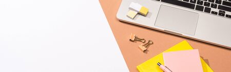 panoramic shot of laptop, notebooks, pen, erasers, paper clips and paper