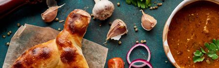 Soup kharcho and adjarian khachapuri with spices and vegetables on textured green background,...