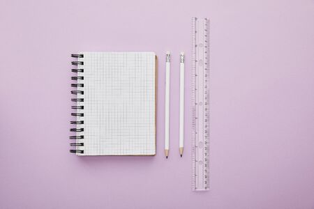 top view of notebook near pencils and ruler isolated on purple