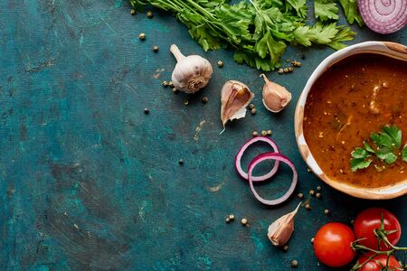 Top view of soup kharcho with cilantro and vegetables on textured green background