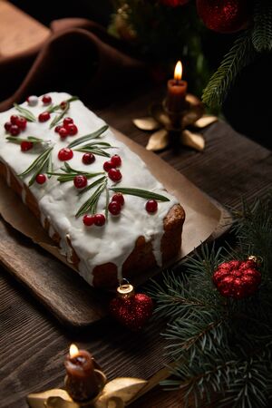 traditional Christmas cake with cranberry near pine with baubles and candles on wooden tableの写真素材