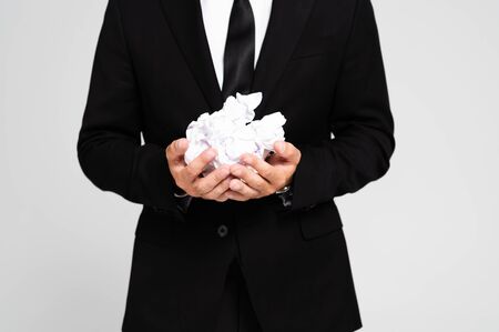 cropped view of businessman in suit holding crumpled papers isolated on greyの写真素材
