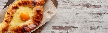Top view of adjarian khachapuri on cutting board on wooden texture, panoramic shotの写真素材