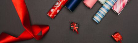 panoramic shot of wrapping paper rolls and little gift boxes on blackの写真素材