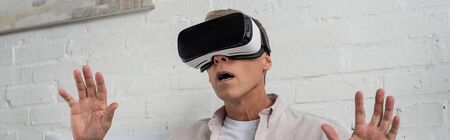 Panoramic shot of exited man in virtual reality headset at home