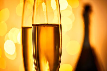 close up of glasses of champagne with blurred yellow christmas lightsの写真素材