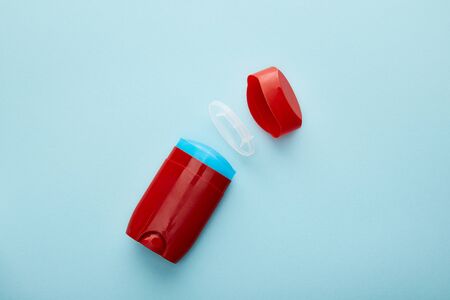 top view of red roll on bottle of deodorant on blue background
