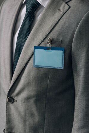 Cropped view of man with badge on grey suit
