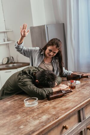 Angry woman quarreling with drunk husband on kitchen
